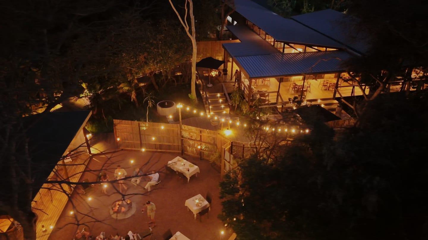 The lodge at night from above, the boma fire, festoon lights and the lit main lodge