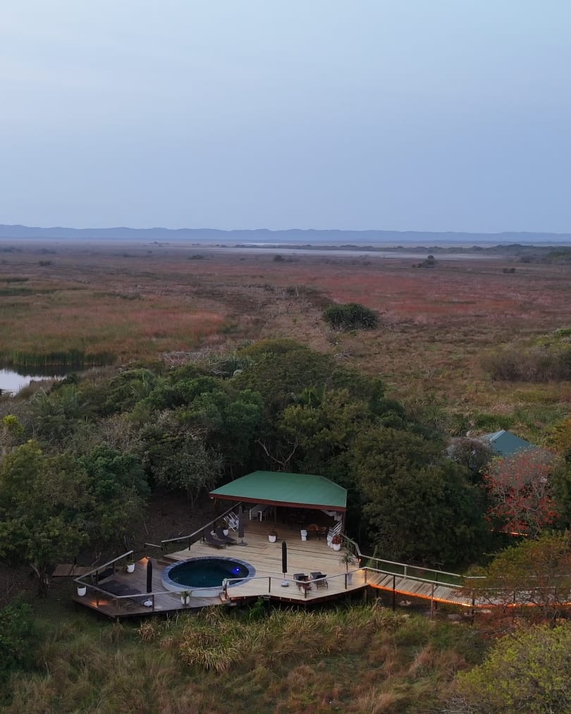 Aerial before sunrise of the pool deck with its lights on, Lake St Lucia and the wetlands beyond