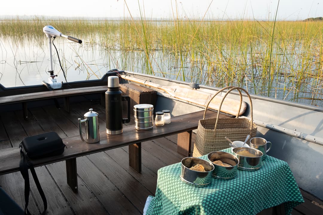 The boat deck laid for coffee with a flask, plunger, tins and mugs on a gingham cloth