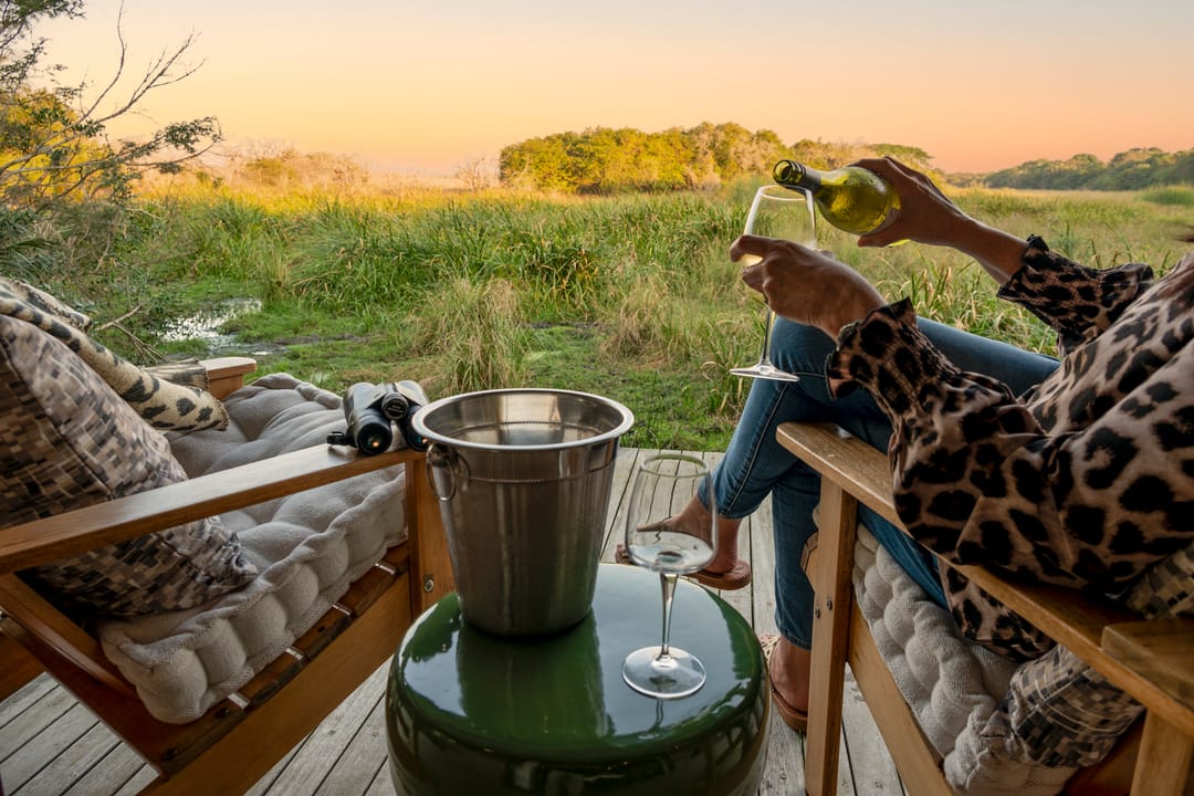 White wine poured on a suite deck at golden hour, binoculars and an ice bucket beside the chairs