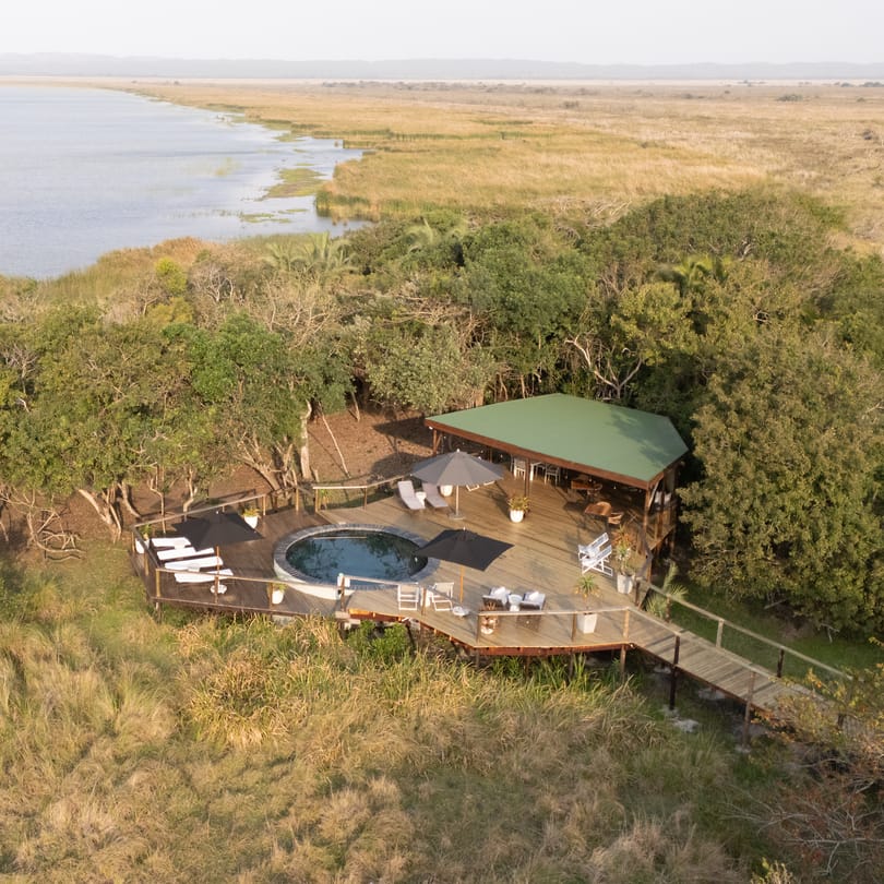 The pool deck and its green-roofed lounge at the edge of Lake St Lucia, seen from the air
