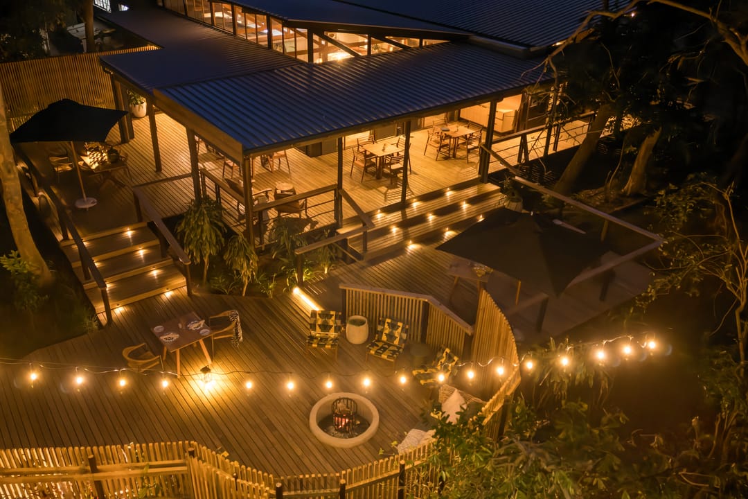 The main lodge and its extended deck at night, string lights glowing through the trees