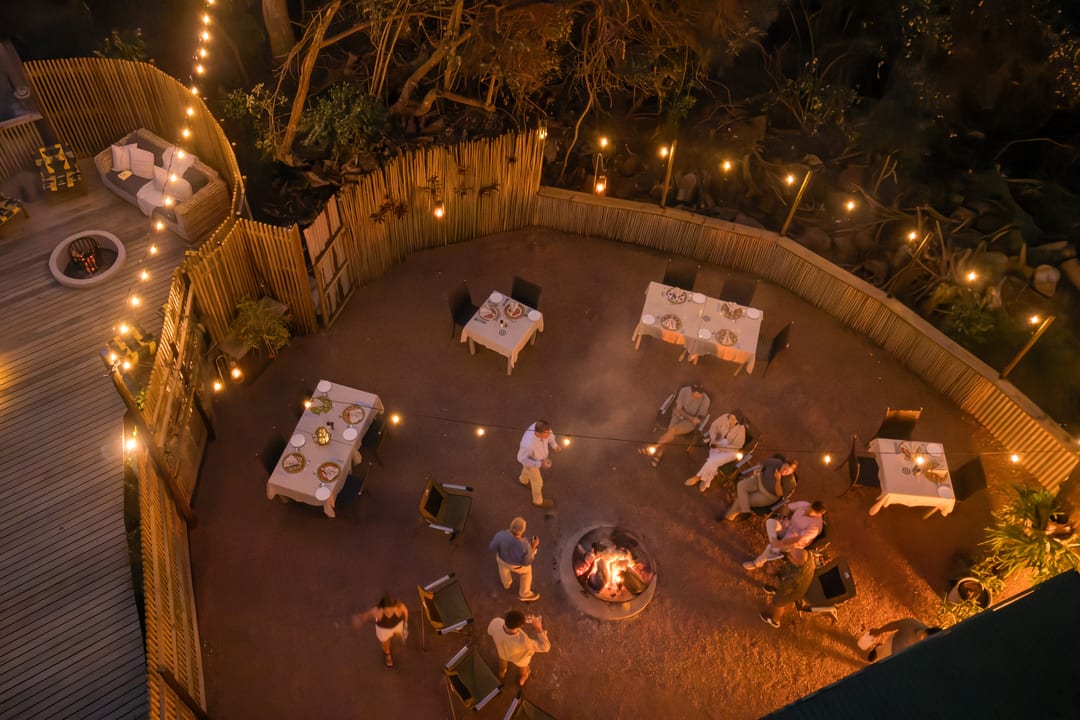 Looking straight down on the main boma at night, guests seated around the central fire