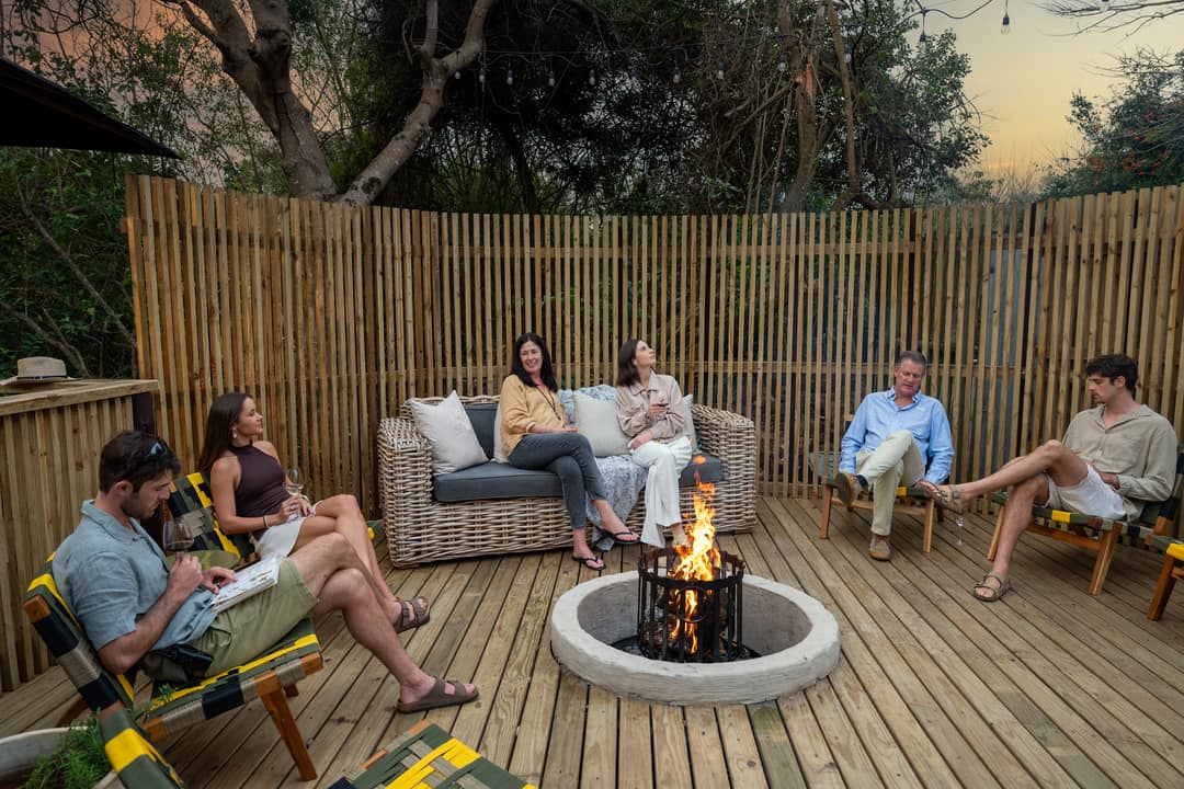 Guests relax around the fire pit of the deck boma as dusk falls