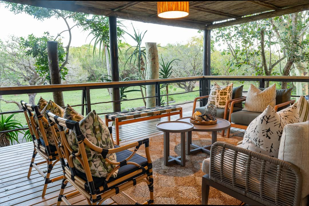 The veranda of the main lodge with cane chairs, patterned cushions and a low coffee table