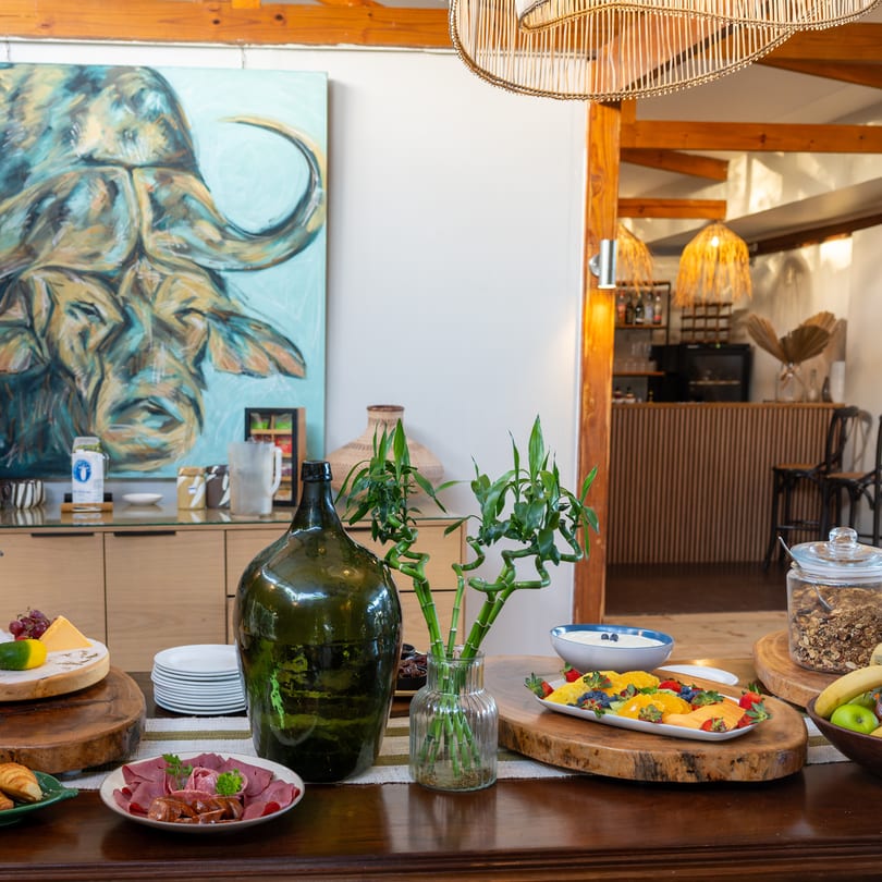 Breakfast laid out in the dining room: croissants, cheese, fruit and cereals on timber boards