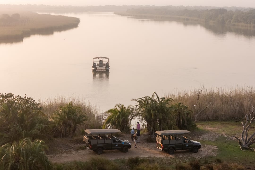 The roofed boat arrives at the boat pick-up point where vehicles and guests wait among palms