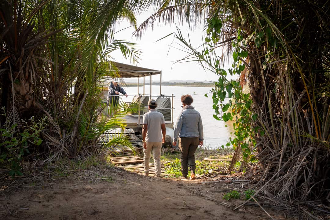 Guests walk a palm-framed path down to the moored boat at the boat pick-up point
