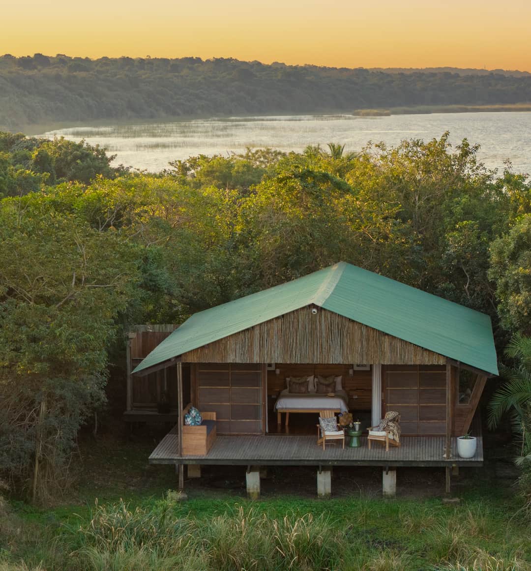 The Honeymoon Suite alone in the coastal forest at sunset, with Lake St Lucia beyond the trees.