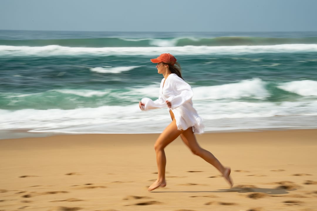 A guest runs along the shore in a white shirt, the surf blurred green behind her